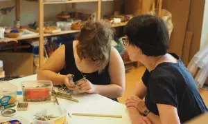 Zwei Frauen arbeiten in einer Lernwerkstatt im Kindergarten. Eine baut mit kleinen Metallteilen.