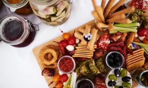 Apetyczna deska owoców na imprezę: ser, oliwki, krakersy, paluszki, warzywa i dipy.