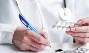Lekarz przepisuje leki na zaburzenia emocjonalne, trzymając blister tabletek i pisząc receptę.