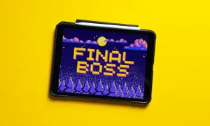 Tablet z grą retro, na ekranie napis "FINAL BOSS" w pikselowej grafice, nocny krajobraz z księżycem i chmurami.