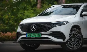 Biały Mercedes EQA z zieloną tablicą rejestracyjną WW 099TN na tle zieleni.
