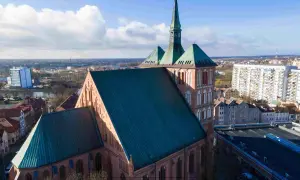 Imponująca katedra góruje nad panoramą jednego z miast w zachodniopomorskim. W tle widać blokowiska i inne budynki.