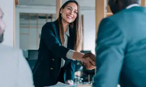 Donna sorridente stringe la mano a un collega, un momento chiave per l'employee experience.