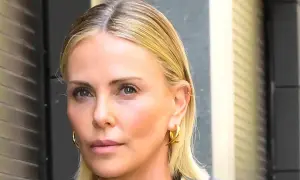 Charlize Theron, bez męża, w złotych kolczykach, patrzy wprost.