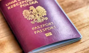 Ciemnoczerwony paszport biometryczny Rzeczypospolitej Polskiej z godłem i napisem "PASZPORT PASSPORT" na drewnianym tle.