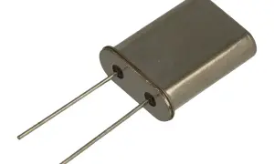 Metalowa obudowa z dwoma pinami, typowy rezonator kwarcowy, kluczowy element w elektronice do stabilizacji częstotliwości.