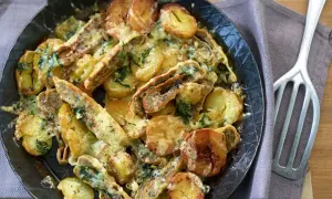 Herzhafte Maultaschen-Pfanne mit goldbraunen Kartoffelscheiben und geschmolzenem Käse, garniert mit frischen Kräutern.
