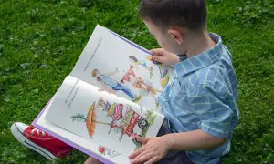 Chłopiec z zaciekawieniem czyta książkę z ilustracjami, która jest częścią bajkoterapii w przedszkolu.