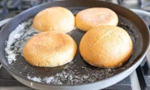 Cztery bułki do burgerów podsmażane na patelni z masłem.