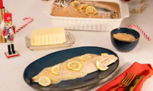 Un bar en croûte de sel, tel que préparé par Julie, est servi avec des rondelles de citron. Un beurre crémeux et une sauce à la moutarde complètent ce plat festif.
