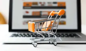 Miniaturowy wózek na zakupy przed ekranem laptopa symbolizuje najpopularniejsze sklepy internetowe i wygodne zakupy online.