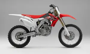 Czerwono-biały motocykl crossowy Honda z widocznym silnikiem i kołami.