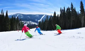 Skifahrer genießen die Pisten in Spindleruv Mlyn. Ein sonniger Tag mit Blick auf die Berge und den Wald.