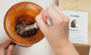 Mielenie ziaren kawy do nalewki z kawy w moździerzu. Obok paczka kawy Darvea Burundi AA.