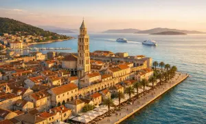 Widok na Split i okolice, z widoczną katedrą św. Dominika, palmami i statkami na morzu. Idealne miejsce na wakacje.