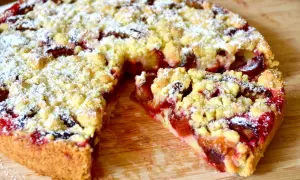 Saftiger Zwetschgenkuchen aus Hefeteig in einer Springform, bestreut mit Puderzucker und Streuseln.