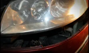 Reflektor Passat B5 FL, widok na żarówki przód. Widać fragment czerwonego lakieru i wnętrze lampy.
