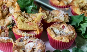 Fluffiga rabarber muffins med mandelflagor och pudersocker, bakade i rosa muffinsformar.