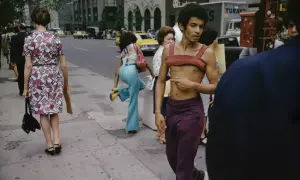 Ulica Nowego Jorku uchwycona przez Joel Meyerowitz. Mężczyzna w bordowym topie i fioletowych spodniach, obok kobiety w kwiecistej sukience.