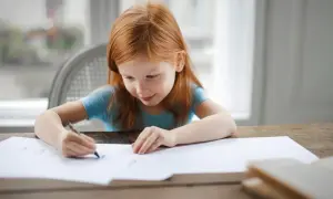 Ruda dziewczynka rysuje. Jej skupienie i zaangażowanie to cechy, które doceni każdy pedagog specjalny, posiadający odpowiednie kwalifikacje.