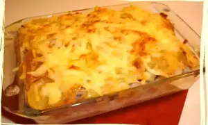 Un plat gratiné de parmentier de cabillaud, avec une couche dorée de fromage fondu, prêt à être dégusté.