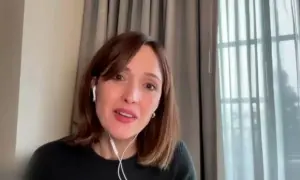 Rose Byrne w jednym ze swoich filmów, w białych słuchawkach, z uśmiechem na twarzy.