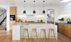 Cocinas con isla y salón modernos, con isla blanca, taburetes de madera y escaleras de diseño.