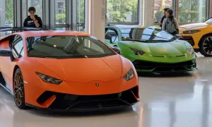 Pomarańczowy i zielony Lamborghini w muzeum Lamborghini. Obok żółty SUV.