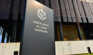 Tablica z napisem "Cour de Justice de l'Union Européenne" przed nowoczesnym budynkiem. To siedziba Trybunału Sprawiedliwości Unii Europejskiej.