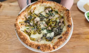 Pizza mit Salsiccia und Friarielli, belegt mit geschmolzenem Käse und geriebenem Parmesan.
