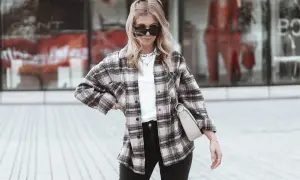 Frau im lässigen Flanellhemd-Style mit Sonnenbrille und Tasche.