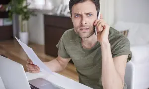 Zmartwiony mężczyzna trzyma dokumenty, rozmawiając przez telefon. Czyżby szykował apelację?