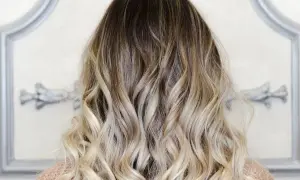Piękne, falowane włosy z efektem ombre blond, przechodzące od ciemnego brązu do jasnego blondu.