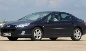 Ciemnoniebieski Peugeot 407 z widocznymi żarówkami reflektorów, kierowca za kierownicą.