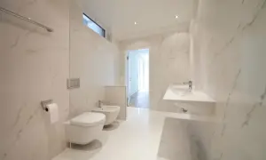 Bagno moderno con bidet e WC sospesi, lavabo a mensola e finiture in marmo. L'altezza scarico bidet è ottimale per un uso confortevole.
