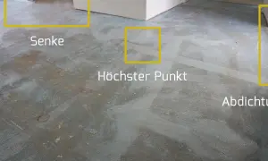 Der Boden wird vorbereitet, um die Ausgleichsmasse zu versiegeln. Markierungen zeigen Senken, den höchsten Punkt und die Abdichtung.