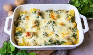 Ein köstlicher Kartoffel-Spinat-Auflauf mit geschmolzenem Käse, bereit zum Servieren. Frische Kartoffeln und Spinat sind die Basis dieses herzhaften Gerichts.