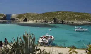 Malta co warto zobaczyć: Błękitna Laguna na Comino, z krystalicznie czystą wodą, łodziami i skalistymi klifami. Idealne miejsce na relaks.