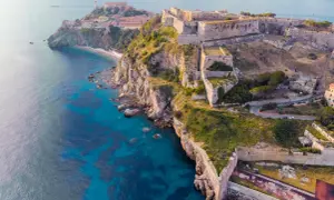Fortificazioni storiche su una scogliera a picco sul mare turchese, un gioiello delle città della Toscana.