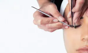 Precyzyjna stylizacja rzęs. Dwie pary pęset tworzą idealne kępki, podkreślając piękno oczu.