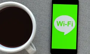 Kawa i smartfon z ikoną Wi-Fi. Zastanawiasz się, jak przyspieszyć internet?