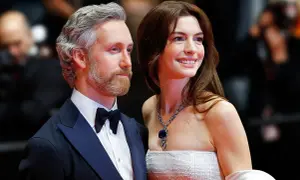 Anne Hathaway z mężem Adamem Shulmanem na czerwonym dywanie. Ona w olśniewającej sukni i biżuterii, on w eleganckim smokingu.
