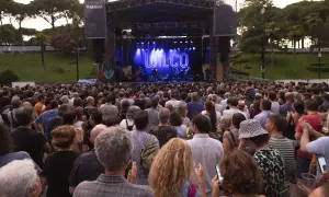 Gran concierto de Wilco en el **jardín de invierno Zaragoza**. Multitud disfruta al aire libre bajo un cielo crepuscular.