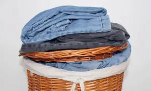 Ein Wäschekorb voller Jeans. Die oberste Jeans stinkt nach Chemie, ein deutliches Zeichen für eine neue Wäsche.