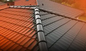 Dach z połową pomalowaną na ciemno, a połową w naturalnym kolorze dachówki.