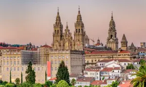 Majestatyczna katedra w Santiago de Compostela góruje nad miastem. W tle widać budynki i palmy.