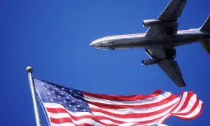 Samolot przelatuje nad flagą USA. Zastanawiasz się, ile trwa lot z Warszawy do Los Angeles?