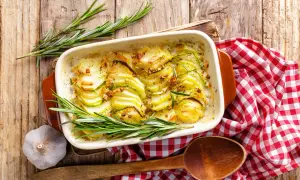 Gratin de pommes de terre et courgettes, une idée pour cuisiner la pomme de terre en 45 recettes originales. Servi avec du romarin et de l'ail.