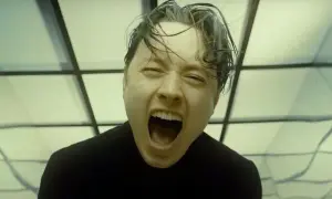 Noah Sebastian screams in a black shirt, his hair wet and messy, against a backdrop of geometric patterns.