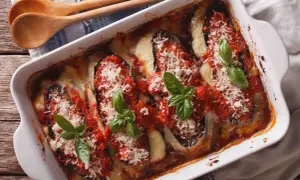 Un plat d'aubergine à la parmesane gratinée, garni de sauce tomate, fromage fondant et basilic frais.